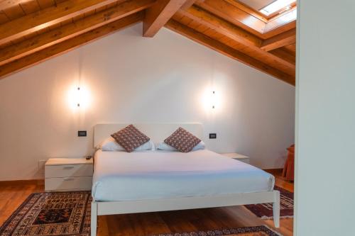 a bedroom with a white bed and wooden ceilings at Hotel Ristorante La Quartina in Mergozzo