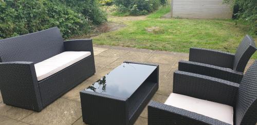 a patio with three chairs and a table with a mirror at Beoley Lodge in Redditch