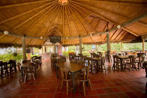 a dining room with tables and chairs under a roof at HOTEL LA SELVA Reserva in La Vega