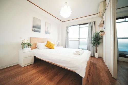 una camera da letto bianca con un letto grande e una finestra di 德川 CU Host CASA ad Osaka