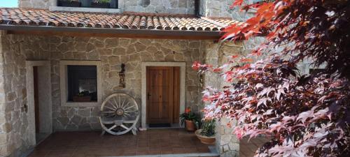 a stone house with a wooden door and a wheel at O Piñón in Santa Cristina de Cobres