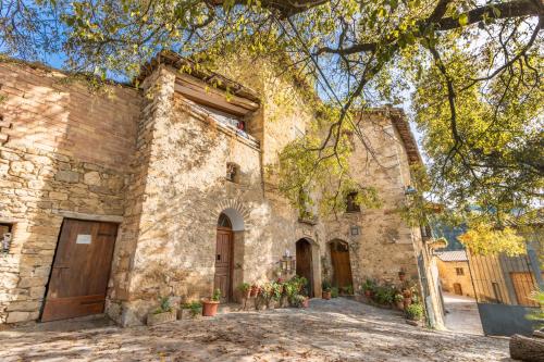 a large stone building with doors and a tree at Casa Roca Sant Martí de Barcedana in Aransís