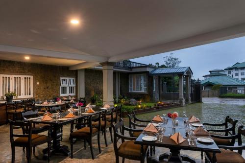 a dining room with tables and chairs and water at Grand Bungalow Nuwara Eliya by Seven Angels in Nuwara Eliya