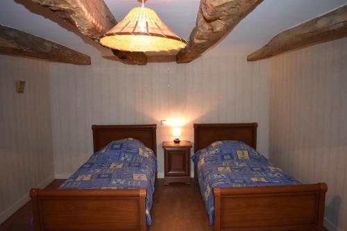 une chambre avec deux lits et un lustre dans l'établissement La Prairie, à La Celle-sous-Gouzon