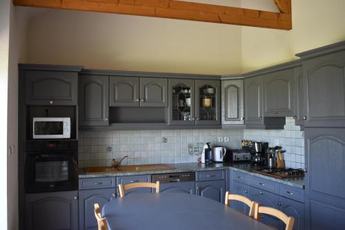 une cuisine avec des placards bleus et une table avec des chaises dans l'établissement La Prairie, à La Celle-sous-Gouzon