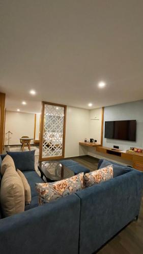 a living room with a blue couch and a flat screen tv at Pristine Pavilion Hotel in Shillong