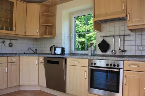 DassowにあるFerienhaus Sandregenpfeiferの木製のキャビネットとコンロ付きオーブンを備えたキッチン