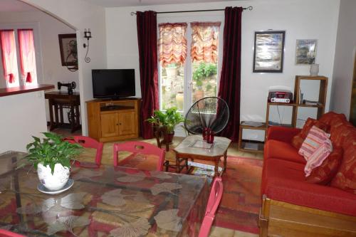 a living room with a red couch and a glass table at Villa hameau paisible Ardouane, à côté voie verte in Riols