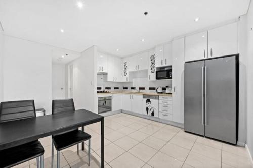 a kitchen with a black table and a refrigerator at Luxury unit near to Sydney CBD and Airport 2b2b1p in Sydney