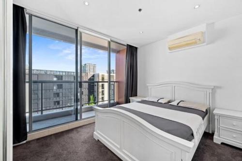 a bedroom with a white bed and a large window at Luxury unit near to Sydney CBD and Airport 2b2b1p in Sydney