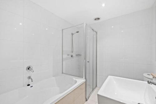 a white bathroom with a shower and a bath tub at Luxury unit near to Sydney CBD and Airport 2b2b1p in Sydney