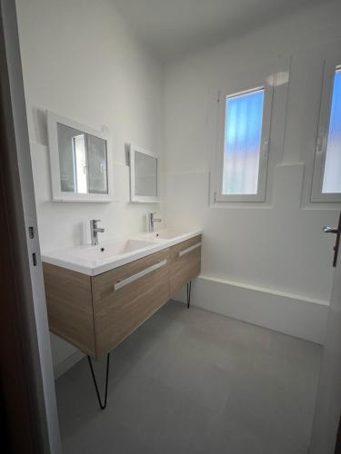 a white bathroom with a sink and two mirrors at Au calme entre mer et montagne in Prades