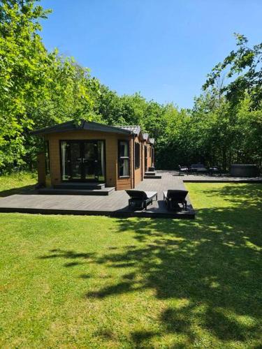 a small cabin in the middle of a grass field at Oak Tree Lodge with Hot Tub near Alton Towers in Croxden
