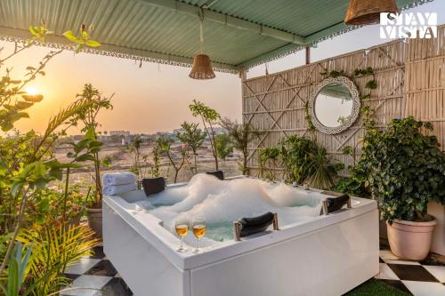 a bath tub with two wine glasses in it at StayVista at Sitara with Jacuzzi & WiFi in Jaipur