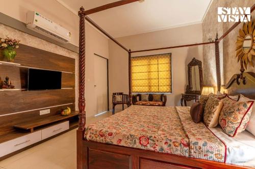 a bedroom with a canopy bed and a television at StayVista at Sitara with Jacuzzi & WiFi in Jaipur