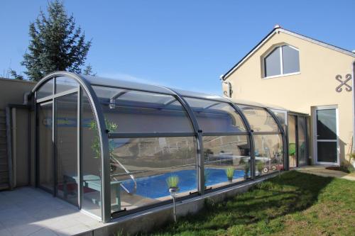 a glass house with a pool inside of it at Doué's Mansion in Doué-la-Fontaine