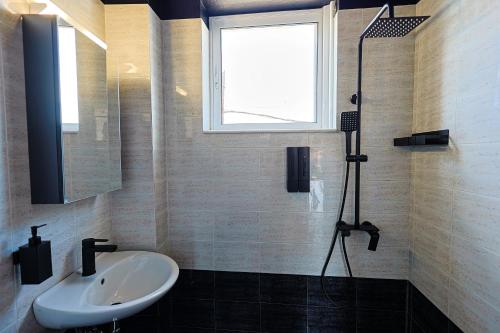 a bathroom with a sink and a shower with a window at AVENA Suites in Kato Gouves
