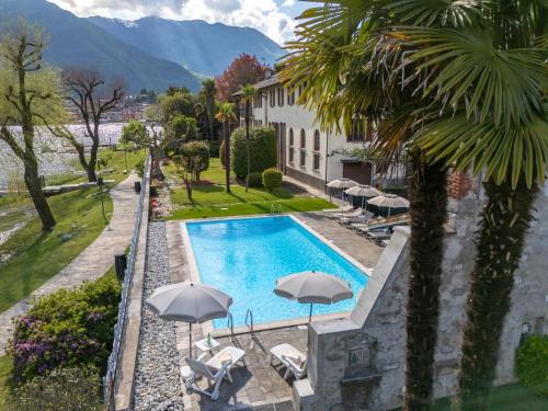 a swimming pool with umbrellas next to a building at Hotel Ristorante La Quartina in Mergozzo