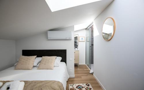 una camera da letto bianca con un letto e uno specchio di Escapade Tropicale fibre, terrasse,parking,clim a Millau