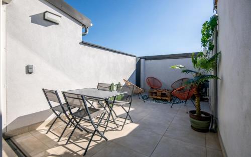un patio avec une table et des chaises sur un balcon dans l'établissement Escapade Tropicale fibre, terrasse,parking,clim, à Millau