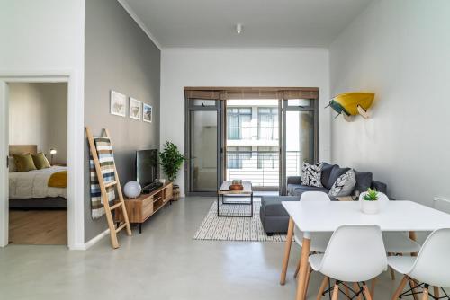 a living room with a couch and a table at Muizenberg Coastal Hideaway by Surfers Corner in Muizenberg