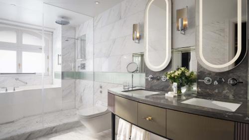 a bathroom with a sink and a toilet and mirrors at Mandarin Oriental Hyde Park, London in London
