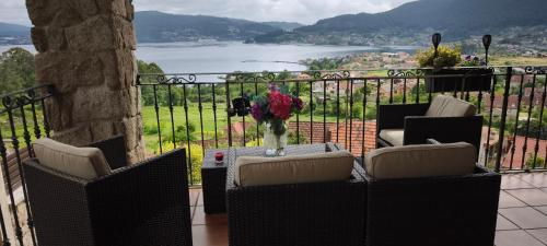 a balcony with two chairs and a vase of flowers at O Piñón in Santa Cristina de Cobres