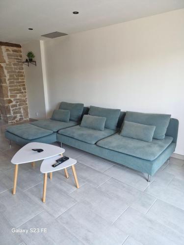a living room with a blue couch and two tables at Maison de village in Vesoul