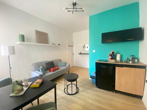 un salon avec un canapé et un mur bleu dans l'établissement Appt RDC Jardin Laverie Parking Villa Margareth, à Dunkerque