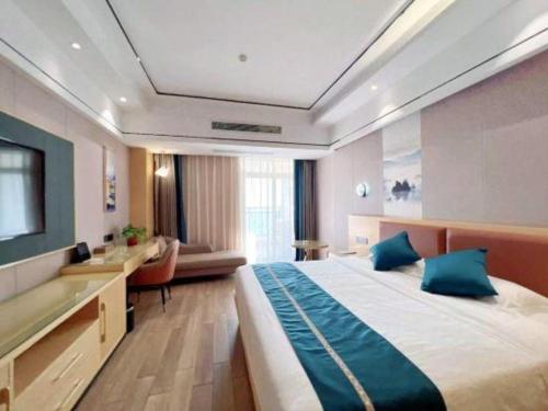 une chambre d'hôtel avec un grand lit et un bureau dans l'établissement Sanya Yellow River Kyoto Hotel, à Sanya