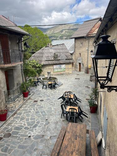 a group of tables and benches on a stone courtyard at Gîte-Auberge l'écureuil in Châteauneuf-dʼEntraunes