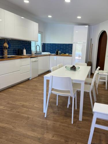 a white kitchen with a white table and chairs at Casa da Ingrina in Raposeira