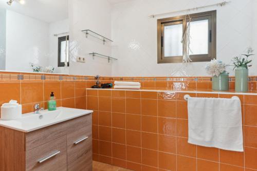 un bagno piastrellato arancione con lavandino e specchio di Casa Centro wifi,aire acondicionado a Mijas