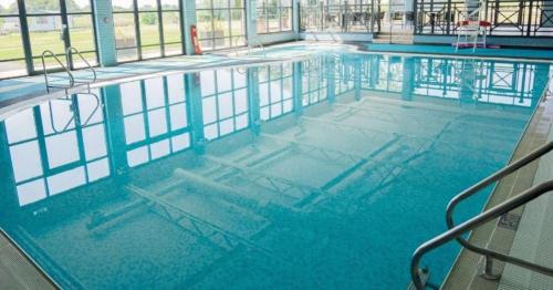 a large swimming pool with blue water in a building at Mill Rythe Coastal Village in South Hayling