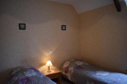 une chambre avec deux lits et une table avec une lampe dans l'établissement Le Pisé, à La Celle-sous-Gouzon