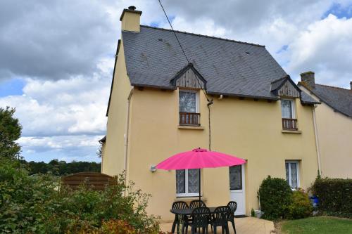 un parapluie rose devant une maison jaune dans l'établissement Le Pisé, à La Celle-sous-Gouzon