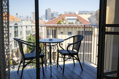 a balcony with a table and chairs and a view of the city at Margosa Boutique Hotel Tel-Aviv Jaffa in Tel Aviv