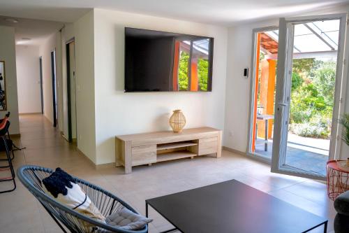 a living room with a tv and a table at Lou Tavan - Villa Rénovée avec Piscine & Jacuzzi - 4 Chambres in Le Lavandou