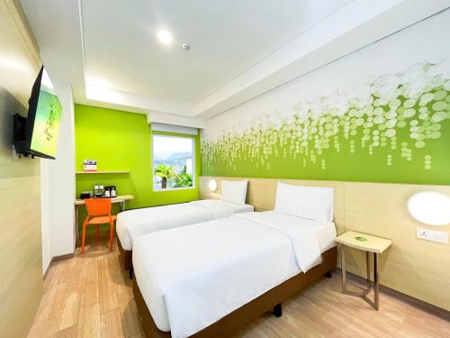 two beds in a room with a green wall at Zest Ambon by Swiss-Belhotel International in Ambon