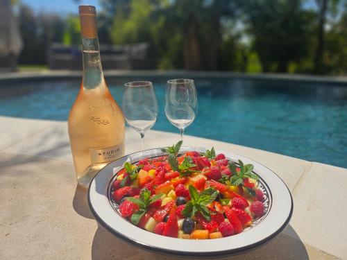 a plate of fruit on a table with a bottle of wine at La Villa 155 superbe appartement centre ville avec piscine in Mandelieu-la-Napoule