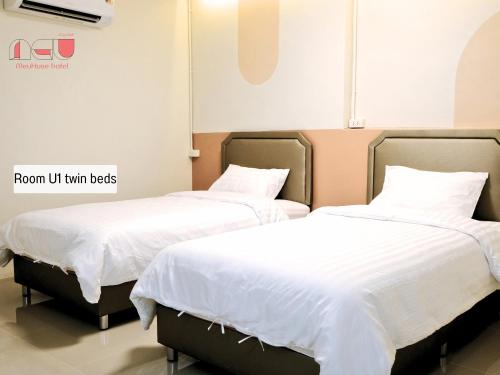 two beds in a room with white sheets and pillows at Me U Huse in Hat Yai