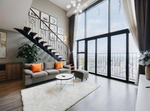 a living room with a couch and a large window at Hi-Home Suites - Penstudio Westlake Hanoi in Hanoi
