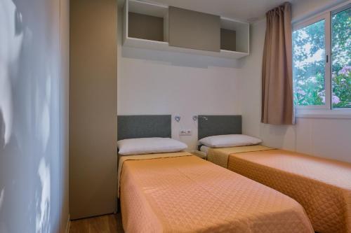 two beds in a small room with a window at Camping Trasimeno in Passignano sul Trasimeno
