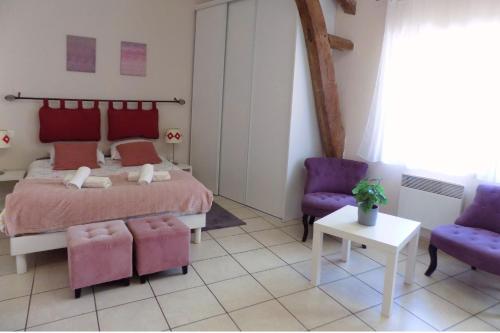 a bedroom with a bed and two purple chairs at Studio Revy 3 - Coeur de Ville in Néris-les-Bains