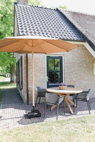 a table and chairs under an umbrella on a patio at Landhuisje in Hoogersmilde