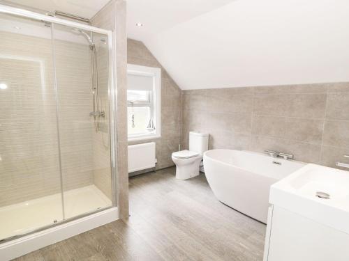 Un baño con bañera, inodoro y ducha. en 51 Trinity Avenue, en Llandudno