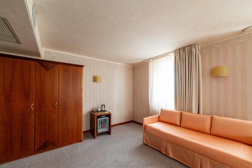a hotel room with an orange couch and a cabinet at Phi Hotel Astoria in Susegana