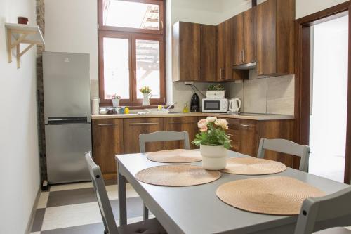 a kitchen with a table with two chairs and a kitchen with a refrigerator at Vadvirág Apartman Gyula in Gyula