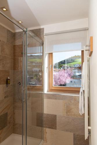 a bathroom with a glass shower with a window at Hotel Heubad in Fiè