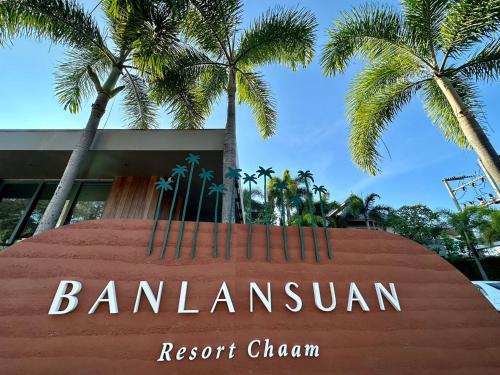 a sign in front of a building with palm trees at Banlansuan Resort SHA Plus in Cha Am